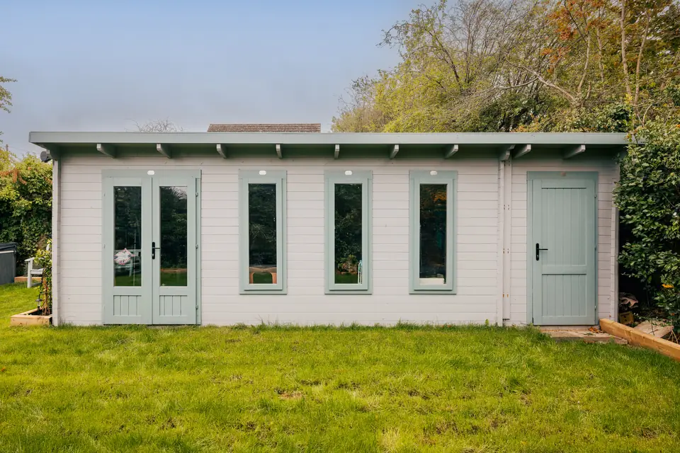 Front of the sage log cabin, with glazed double doors, four windows and a separate side door